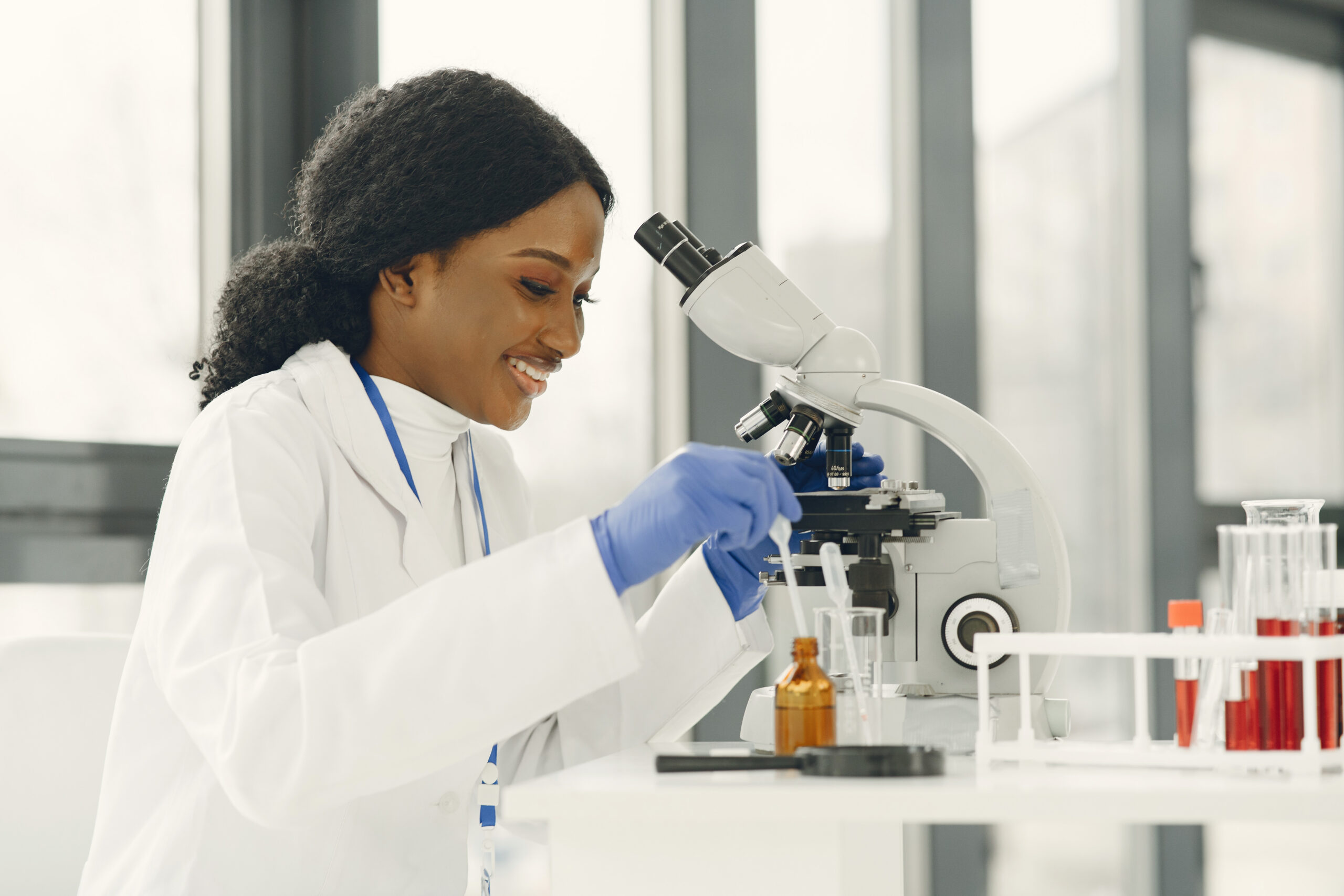 Medical doctor girl working with a microscope. Young female scientist doing vaccine research.